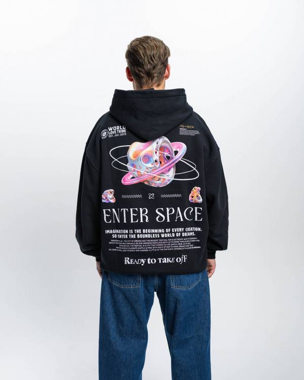 (DE) Ein Mann trägt einen schwarzen Hoodies mit Backprint aus bunte Planeten, Text in weißer Schrift und darüber einem großen Schriftzug "ENTER SPACE". (EN) A man is wearing a black hoodie with a back print of colourful planets, text in white lettering and a large lettering ‘ENTER SPACE’ above it.