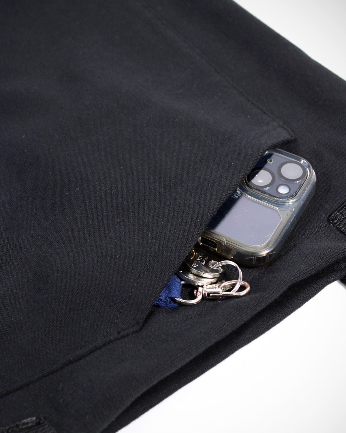 Eine Nahaufnahme auf die Seitentasche des Line-up 2025 Upcycling Beutels. Die Bauchtasche ist senkrecht vernäht und unten geschlossen, so dass sie voll funktionsfähig ist. Zu sehen ist ein rausguckendes Handy sowie ein Schlüssel.