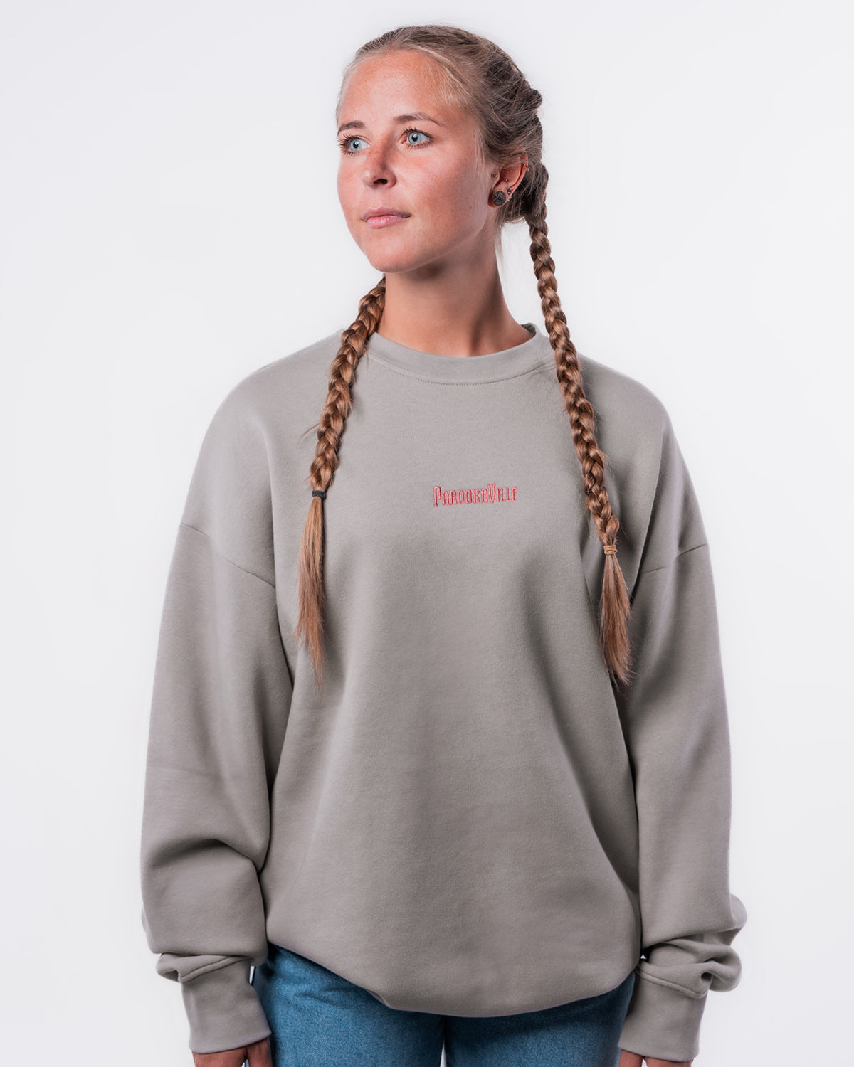 (DE) Eine Frau trägt den grauen Heart Sweater.Vorne steht in dicker roter Schrift die Aufschrift "PAROOKAVILLE". (EN) A woman is wearing the grey Heart Sweater. There is the bold inscription "PAROOKAVILLE" at the front of the sweater.