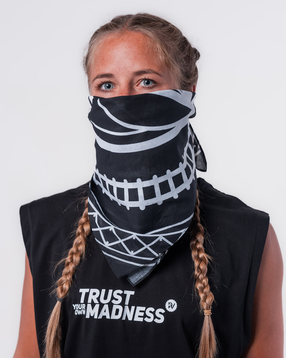 (DE) Eine Frau trägt die Bandana mit Rails Motiv über ihre Nase und ihr Gesicht. Dazu trägt sie das schwarze Muskel Shirt "TRUST YOUR OWN MADNESS". (EN) A woman is covering her nose and the lower part of her face with the bandana with rail motif. She is also wearing the black muscle shirt "TRUST YOUR OWN MADNESS". 