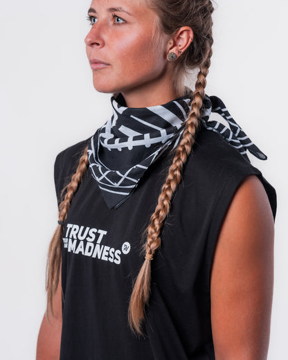 (DE) Eine Frau trägt die Bandana mit Rails Motiv um den Hals und dazu das schwarze MuskelShirt "TRUST YOUR OWN MADNESS". (EN) A woman wears the bandana with rails motif around her neck and the black muscle shirt ‘TRUST YOUR OWN MADNESS’.