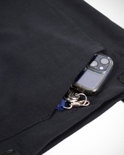 Eine Nahaufnahme auf die Seitentasche des Line-up 2025 Upcycling Beutels. Die Bauchtasche ist senkrecht vernäht und unten geschlossen, so dass sie voll funktionsfähig ist. Zu sehen ist ein rausguckendes Handy sowie ein Schlüssel.