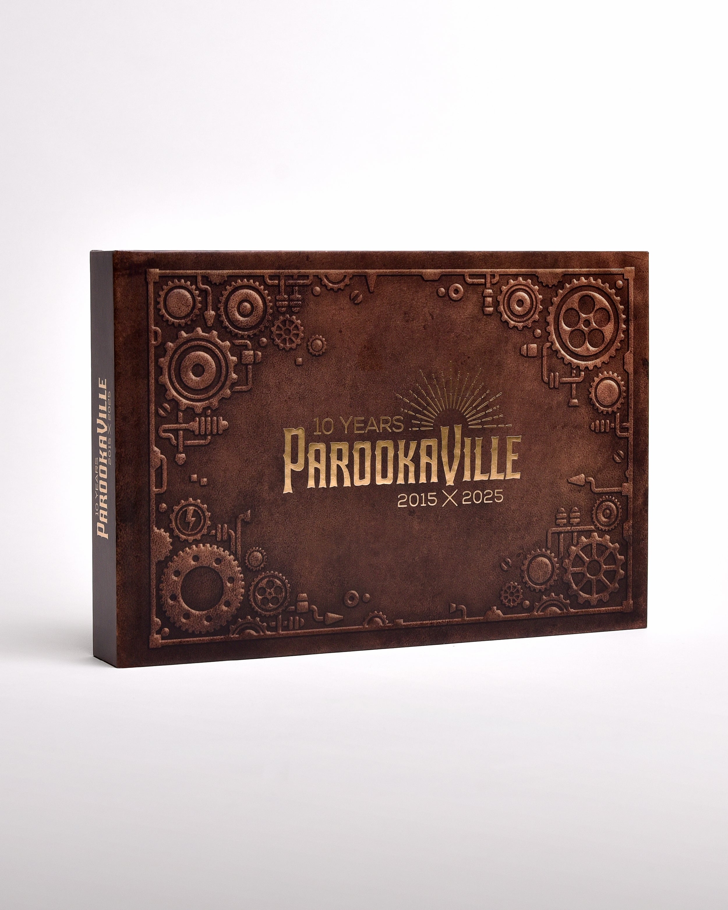 Zu sehen ist die Hülle des Buches im senkrecht-länglichen Format. Sie ist im Stil eines braunen Koffers mit goldenen Ecken gedruckt. Auf dem "Koffer" sind Sticker geklebt. Hier steht ein Sticker für eine Bühne der letzten 10 Jahre.