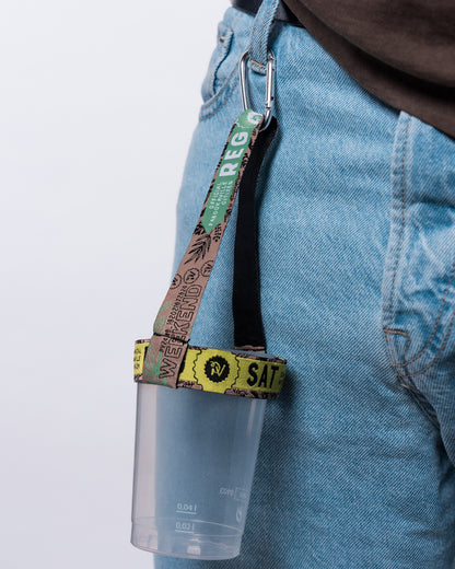 (DE) Man sieht die Nahansicht eines Upcycling Cupholders, welcher an der vorderen Gürtelschlaufe einer Jeans befestigt ist. Die Halterung des Cupholders besteht aus alten Einlassbändchen aus dem Jahr 2024. (EN) One can see a close-up view of the Upcycling Cupholder which is attached to the belt loop of a pair of jeans. It is made out of admission wristbands of 2024. 