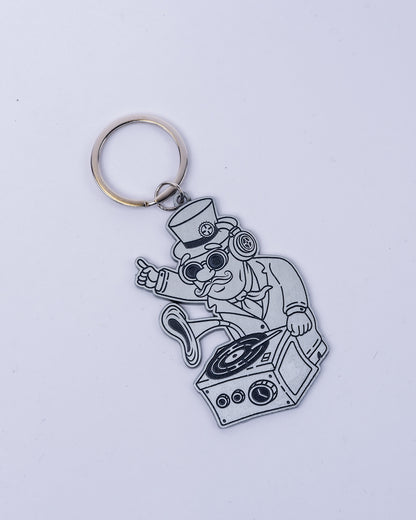 Der silberne DJ-Bill-Schlüsselanhänger zeigt Bill Parooka als DJ mit Zylinder, Brille und Kopfhörern am Grammophon-Mischpult, befestigt an einem Metall-Schlüsselring.